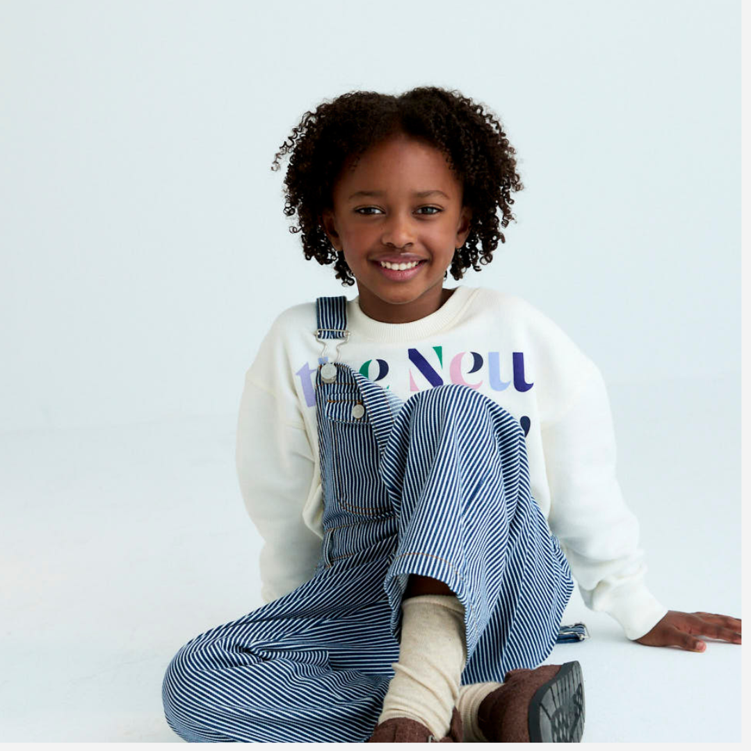 Sold at Bombon Shop, these unisex overalls by The New Society are made from a striped denim with a vintage wash, featuring adjustable shoulder straps, side button closures, and patch pockets for a timeless, relaxed silhouette. model