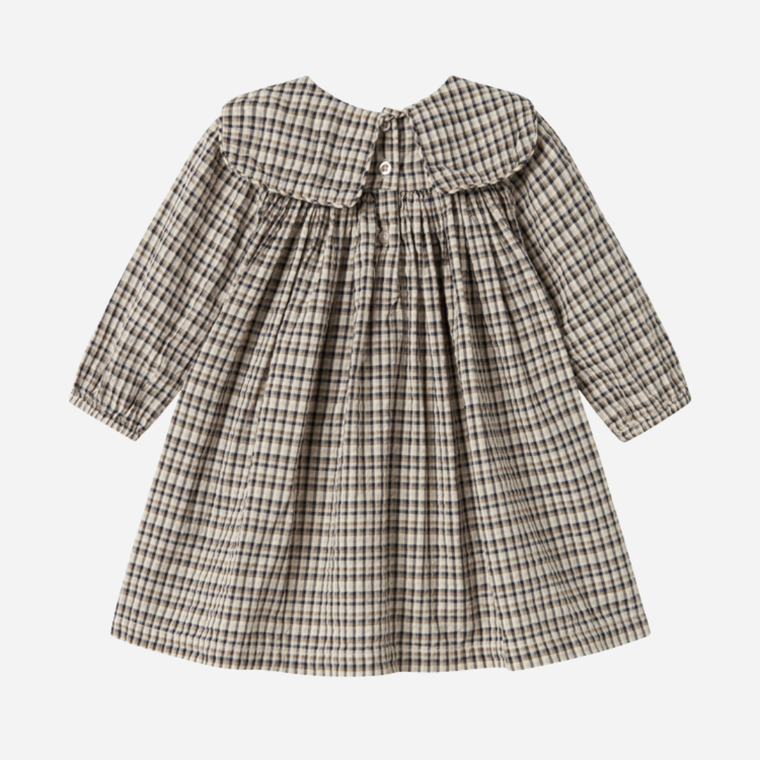 Sold at Bombon shop, designed by MarMar Copenhagen. Beige and navy check long-sleeve cotton dress with gathered yoke and front pockets.