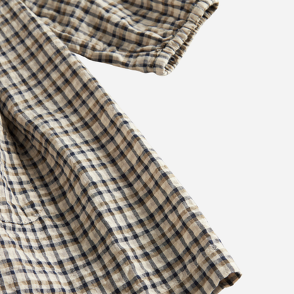 Sold at Bombon shop, designed by MarMar Copenhagen. Beige and navy check long-sleeve cotton dress with gathered yoke and front pockets.