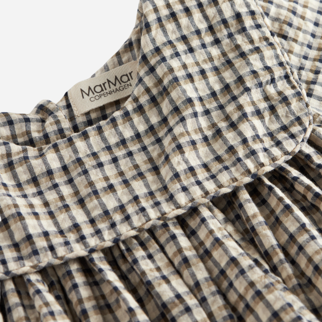 Sold at Bombon shop, designed by MarMar Copenhagen. Beige and navy check long-sleeve cotton dress with gathered yoke and front pockets.
