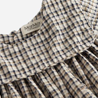 Sold at Bombon shop, designed by MarMar Copenhagen. Beige and navy check long-sleeve cotton dress with gathered yoke and front pockets.