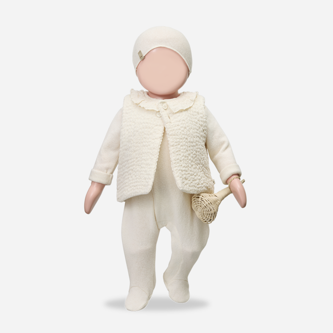 Sold at Bombon shop, designed by 1+ in the family — ecru knit baby beanie with stitched logo tag, laid flat on a white background. mannequin