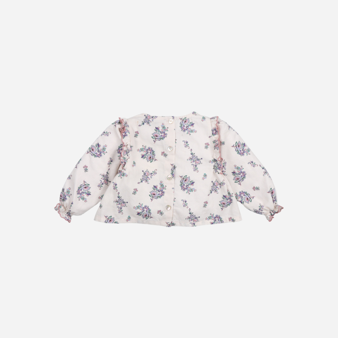 Sold at Bombon shop, this baby girl blouse by The New Society features a delicate floral print on a soft cream base, with ruffle detailing along the chest and shoulders, gathered cuffs, and a flared silhouette for a charming look. back