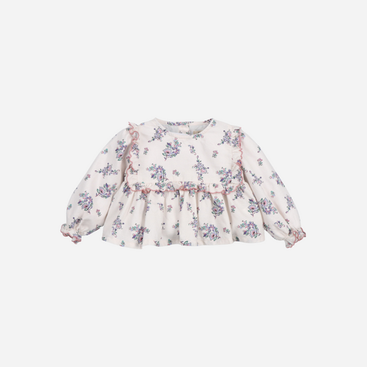 Sold at Bombon shop, this baby girl blouse by The New Society features a delicate floral print on a soft cream base, with ruffle detailing along the chest and shoulders, gathered cuffs, and a flared silhouette for a charming look. front