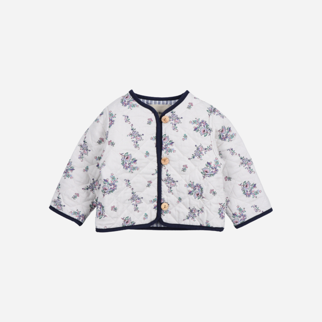 Sold at Bombon shop, this baby girl quilted jacket by The New Society showcases a sweet floral print with wooden buttons and contrasting navy trim—perfect for layering in cooler weather while adding a classic touch. front