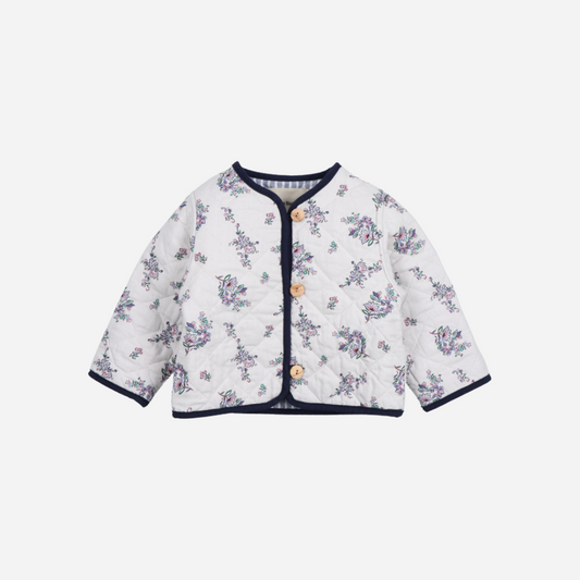 Sold at Bombon shop, this baby girl quilted jacket by The New Society showcases a sweet floral print with wooden buttons and contrasting navy trim—perfect for layering in cooler weather while adding a classic touch. front
