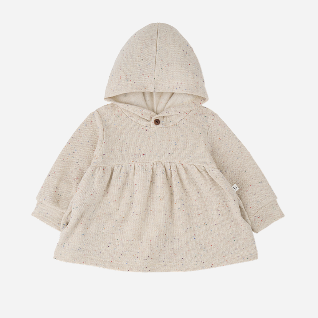 Sold at Bombon shop, designed by 1+ in the family — long-sleeve speckled beige baby dress with gathered waist and hood, shown flat on white background. front