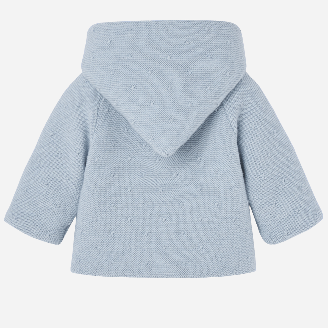 Sold at Bombon shop, designed by Paz Rodriguez, blue knit hooded baby coat with dot texture and button-up front from the Erizos collection.