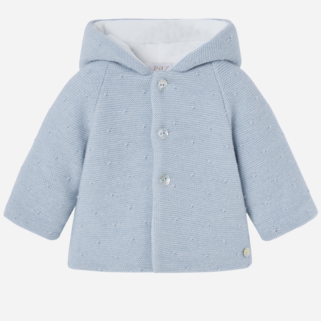 Sold at Bombon shop, designed by Paz Rodriguez, blue knit hooded baby coat with dot texture and button-up front from the Erizos collection.