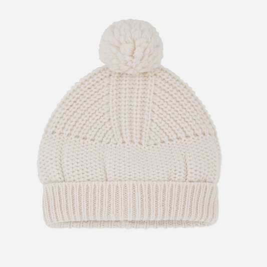 Knitted beanie with a pom-pom on a light gray background
