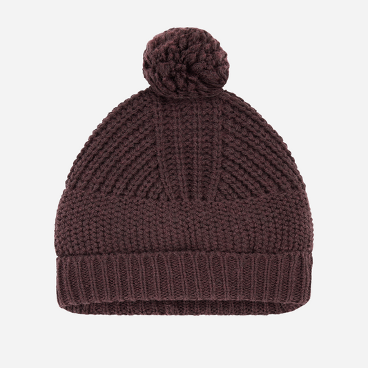 Sold at Bombon shop, designed by 1+ in the family — dark purple melanzana knit baby beanie with pom-pom and wide fold-over brim, displayed flat on a white background. front