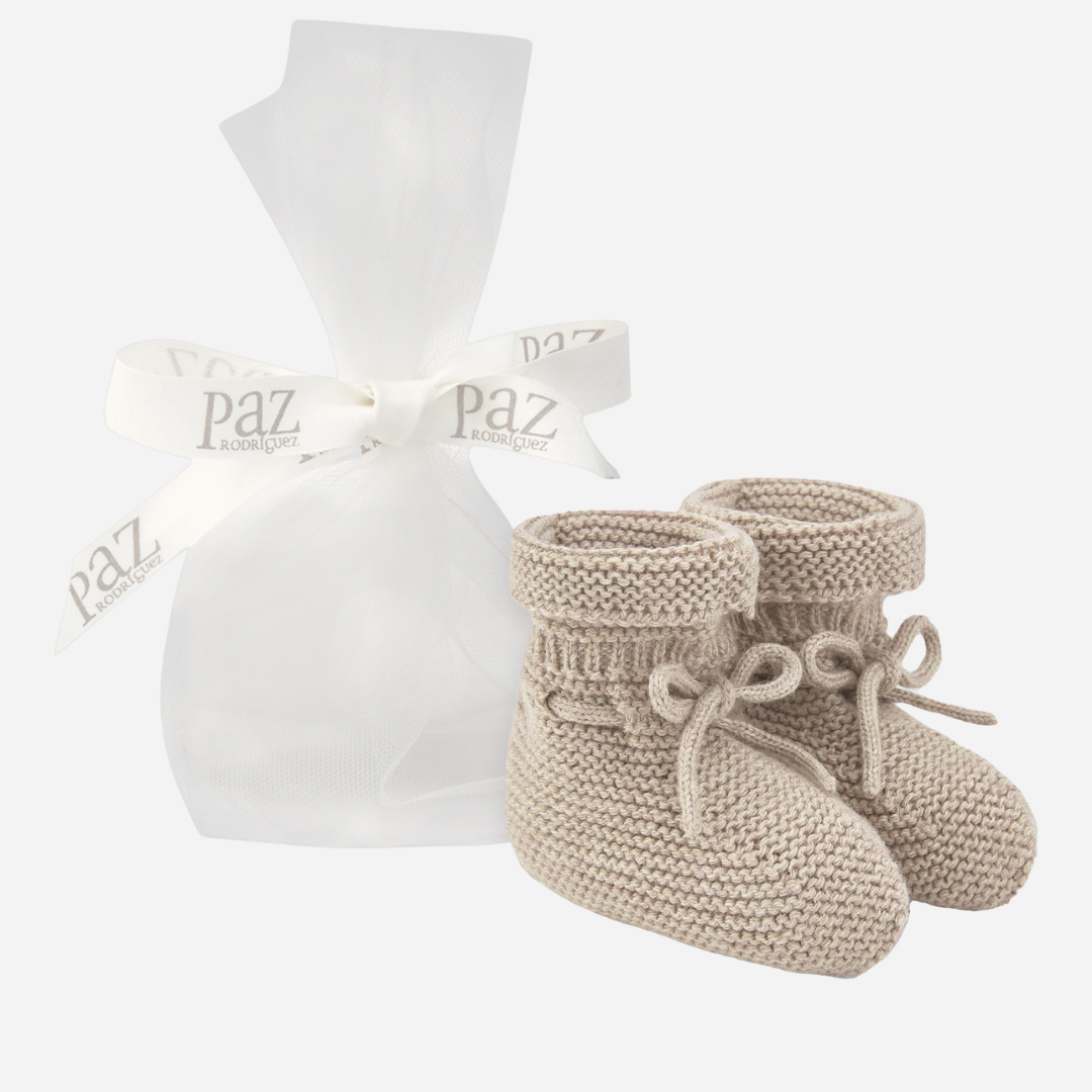 Sold at Bombon shop, designed by Paz Rodriguez. Beige knit baby booties with tie detail and rolled cuff.