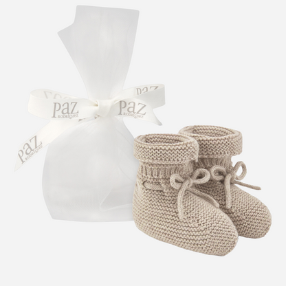 Sold at Bombon shop, designed by Paz Rodriguez. Beige knit baby booties with tie detail and rolled cuff.
