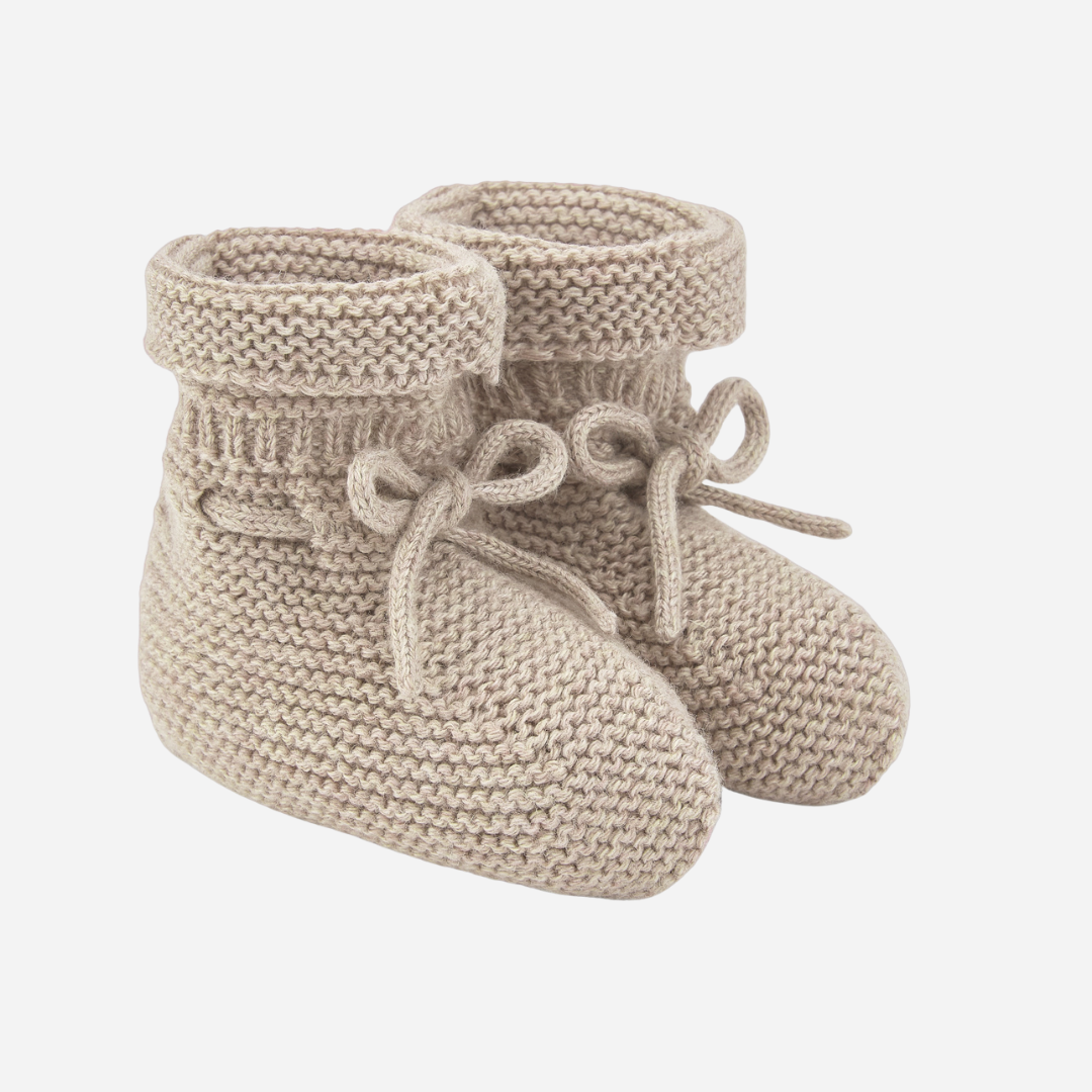 Sold at Bombon shop, designed by Paz Rodriguez. Beige knit baby booties with tie detail and rolled cuff.
