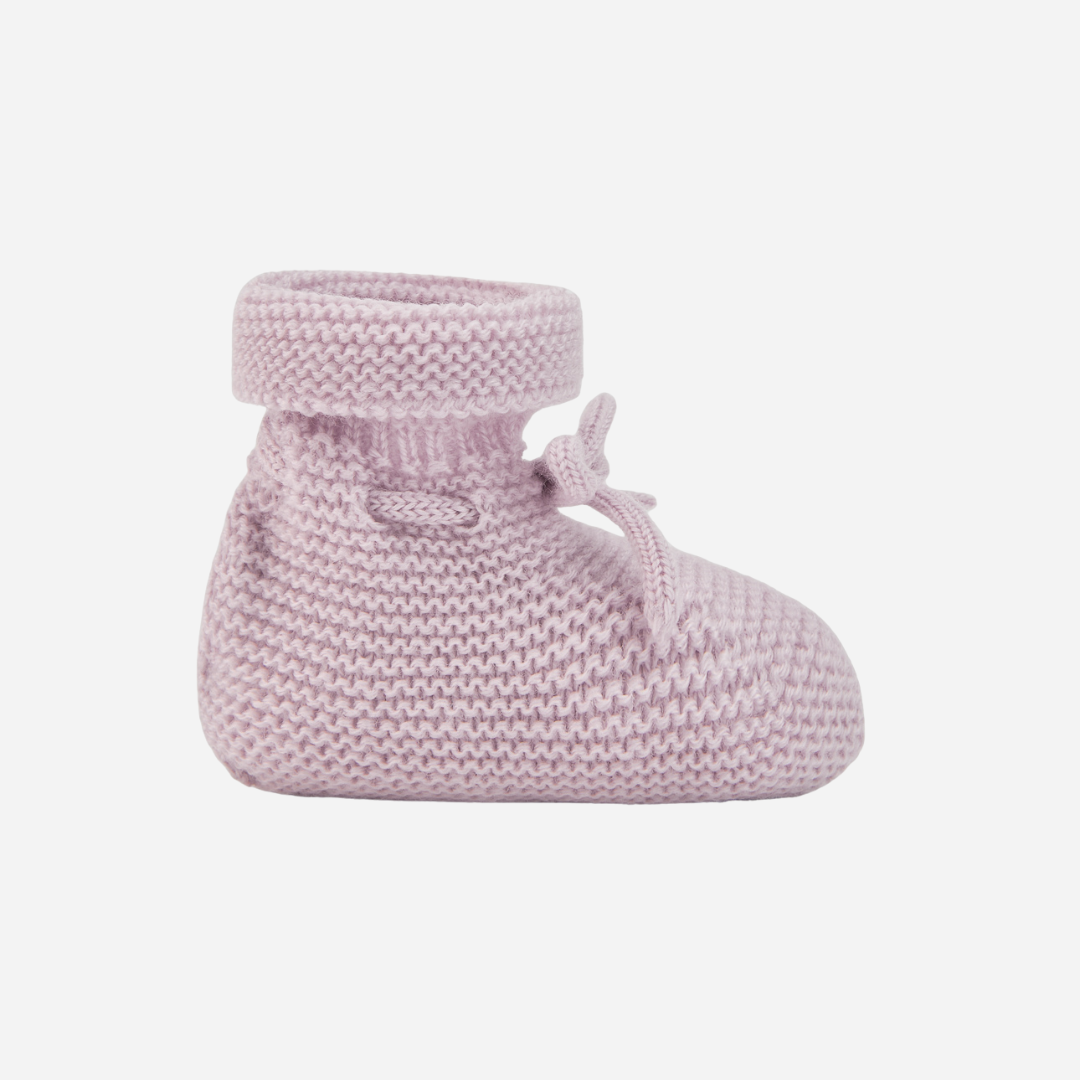 Sold at Bombon shop, designed by Paz Rodriguez. Pale pink knit baby booties with tie detail and rolled cuff side view