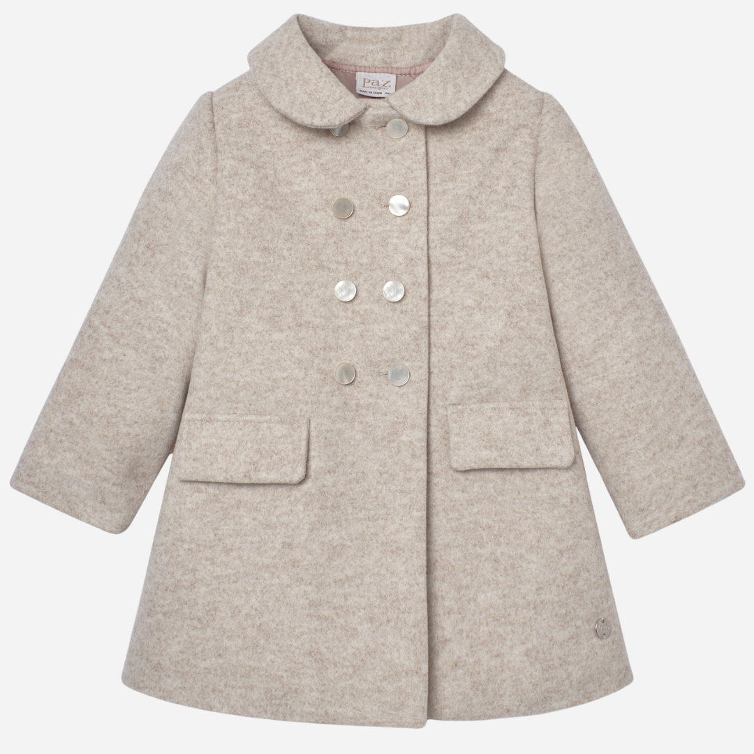 Sold at Bombon shop, designed by Paz Rodriguez, beige wool girl’s coat with double-breasted buttons and rounded collar.