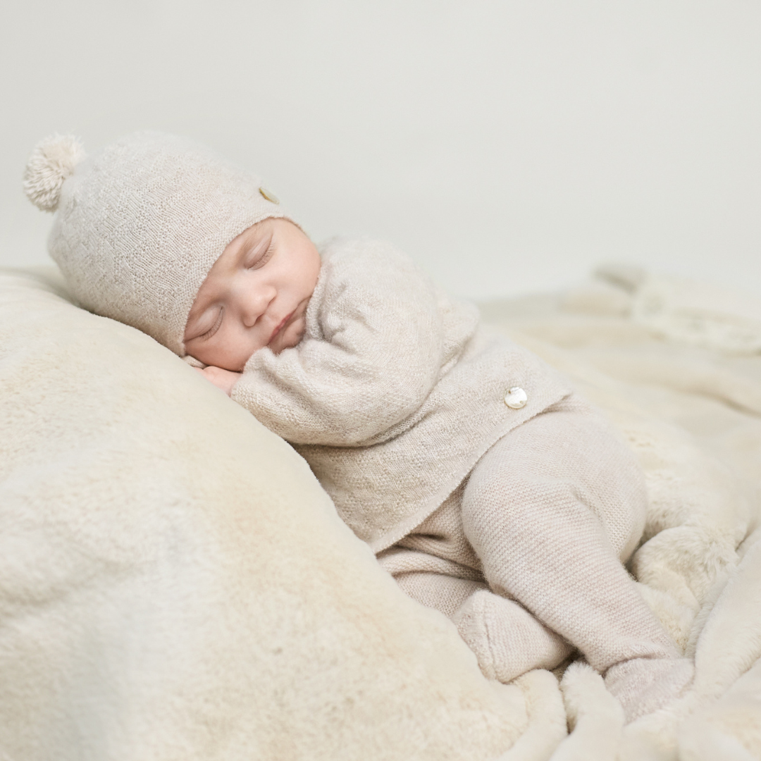 Sold at Bombon shop, designed by Paz Rodriguez. Beige baby knit two-piece set with sweater and footed pants in a soft textured pattern.