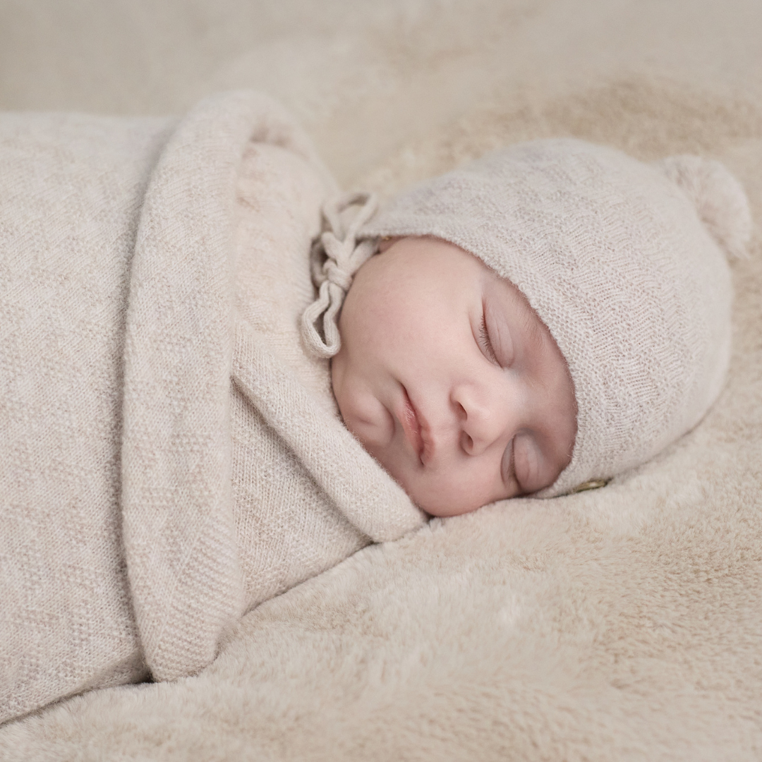 Sold at Bombon shop, designed by Paz Rodriguez. Beige knit baby hat with pompom and chin ties, perfect for cold weather.