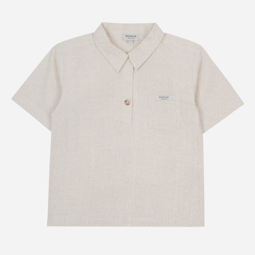 Sold at Bombon shop, designed by Donsje from Amsterdam, this baby and toddler short sleeve button down shirt in a warm white color for boys is the perfect pre-fall and transition piece. front view