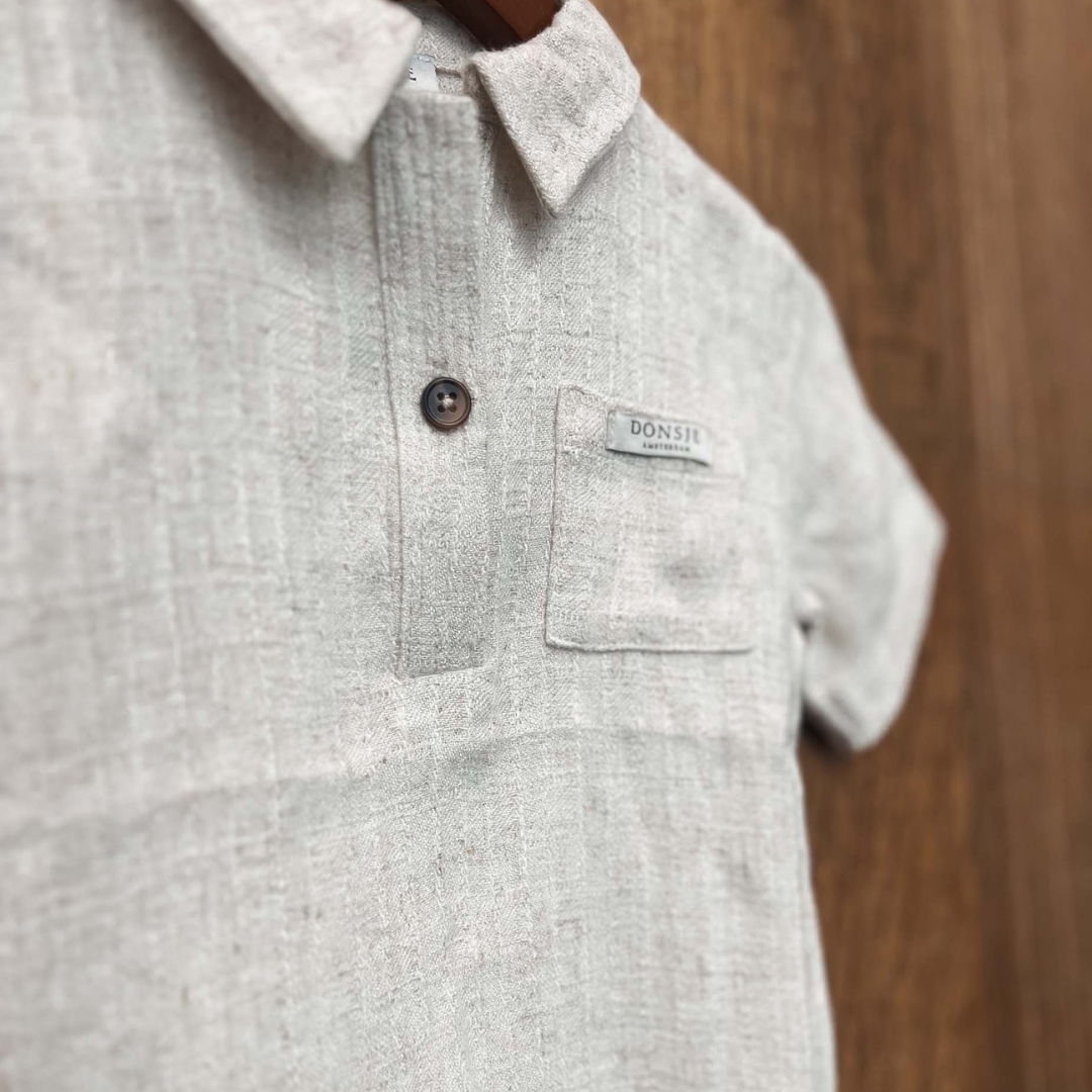 Sold at Bombon shop, designed by Donsje from Amsterdam, this baby and toddler short sleeve button down shirt in a warm white color for boys is the perfect pre-fall and transition piece. hanging view