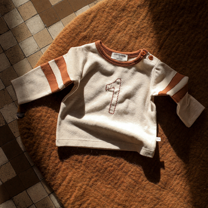 White sweater with brown accents on a textured surface
