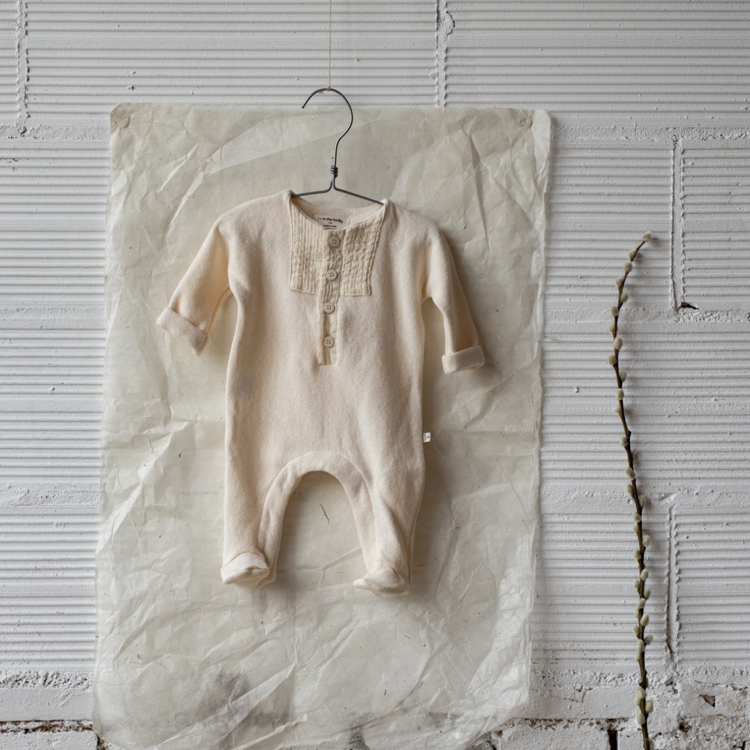 Sold at Bombon shop, designed by 1+ in the family — ecru footed baby jumpsuit with button placket and long sleeves. lifestyle