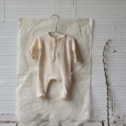 Sold at Bombon shop, designed by 1+ in the family — ecru footed baby jumpsuit with button placket and long sleeves. lifestyle