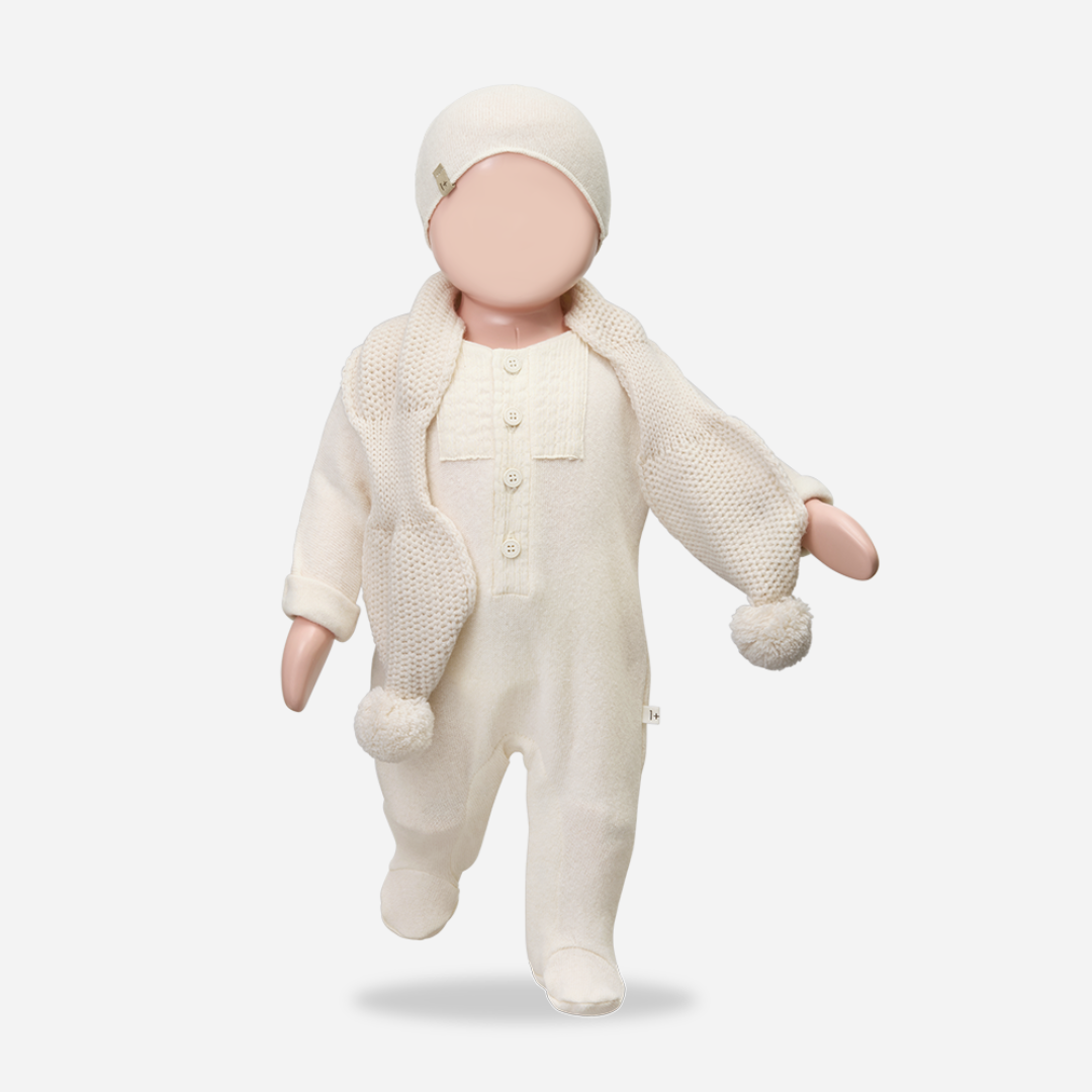 Sold at Bombon shop, designed by 1+ in the family — ecru footed baby jumpsuit with button placket and long sleeves. mannequin