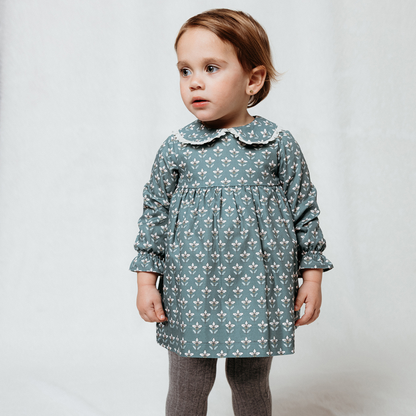 Sold at Bombon shop, designed by Fina Ejerique, a sage green floral baby dress with lace-trim collar and long sleeves. model