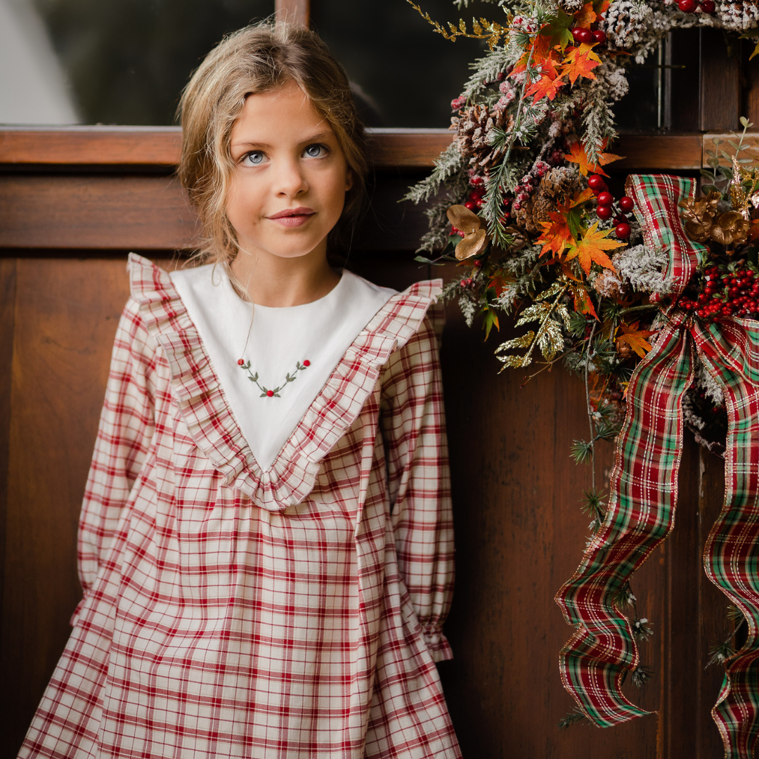 Sold at Bombon shop, designed by Paz Rodriguez, baby and toddler red plaid dress with white embroidered holly collar and ruffle details from the Acebo holiday collection.