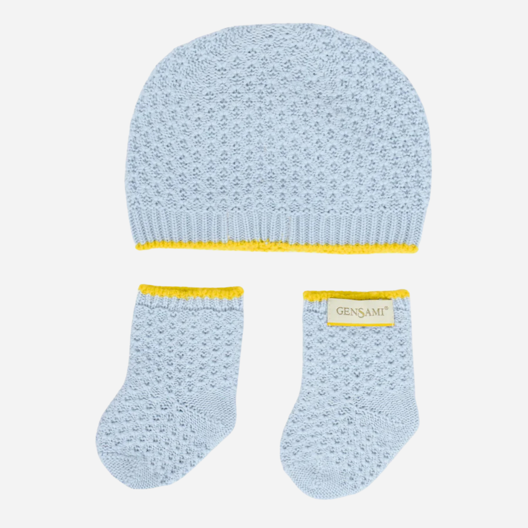 Sold at Bombon and designed by Gensami, a blue knit baby hat and booties set with yellow trim, made from soft cotton.