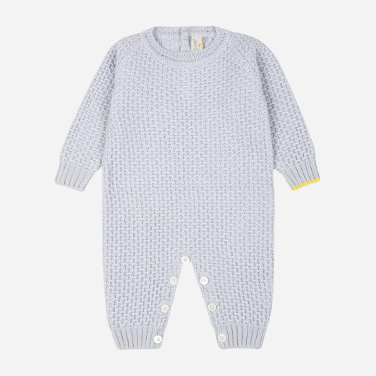 Sold at Bombon and designed by Gensami, a blue cotton knit baby jumpsuit with a yellow trim accent at the cuff.