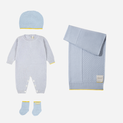 Sold at Bombon and designed by Gensami, a soft blue newborn layette set with a knit jumpsuit, hat, booties, and blanket, detailed with yellow edging