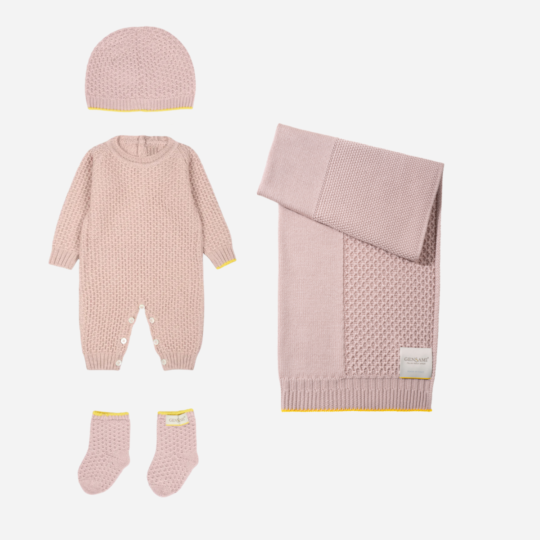 Sold at Bombon and designed by Gensami, a soft pink knit layette set with jumpsuit, hat, booties, and blanket, accented with yellow trim