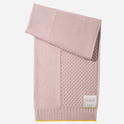 Sold at Bombon and designed by Gensami, a soft pink knit layette set with jumpsuit, hat, booties, and blanket, accented with yellow trim