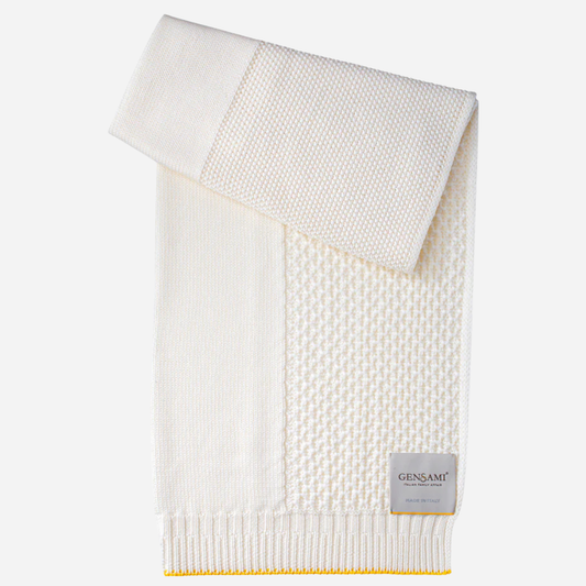 Sold at Bombon and designed by Gensami, an ivory knit baby blanket with a yellow trim