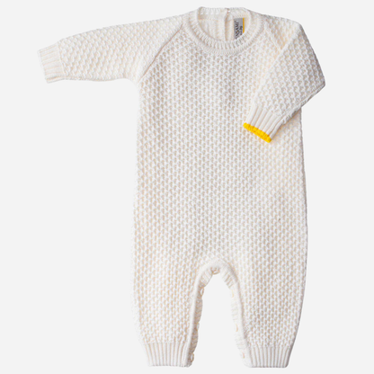 Sold at Bombon and designed by Gensami, an ivory newborn layette set including a knit jumpsuit, hat, booties, and blanket with yellow trim