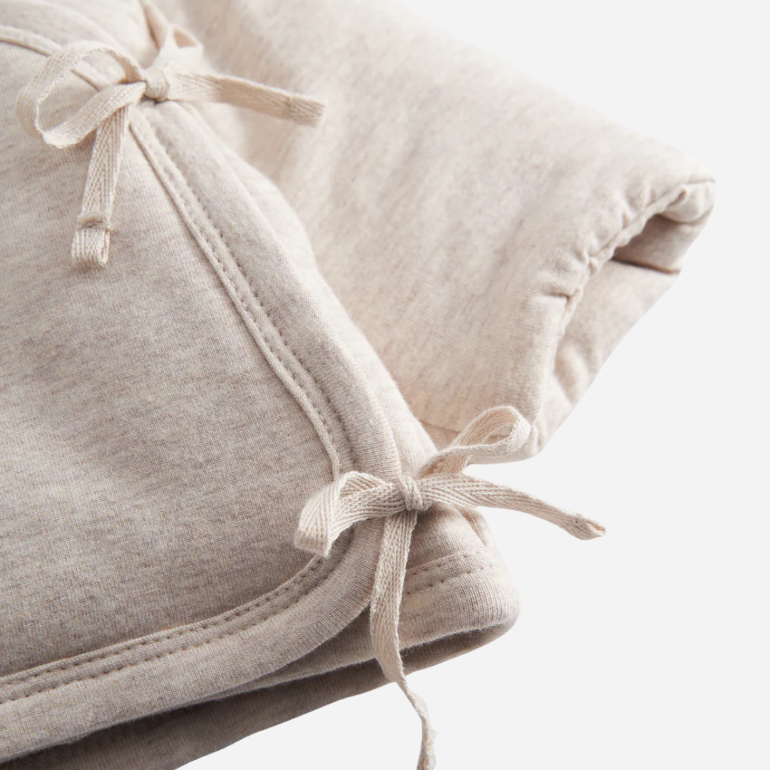 Sold at Bombon shop, designed by MarMar Copenhagen — beige organic cotton baby jacket with hood and side tie closure.