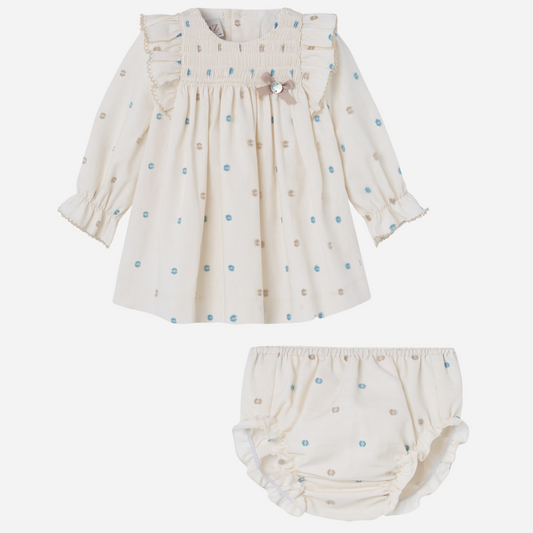 Sold at Bombon shop, designed by Paz Rodriguez. Baby girl dress and bloomer set in ivory with embroidered blue and taupe dots, smocked chest, and ruffled sleeves.