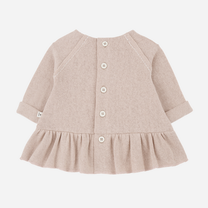 Sold at Bombon shop, designed by 1+ in the family — nude long-sleeve baby dress with ruffled hem and front patch pocket. back