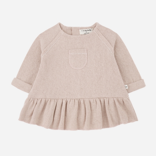 Sold at Bombon shop, designed by 1+ in the family — nude long-sleeve baby dress with ruffled hem and front patch pocket.