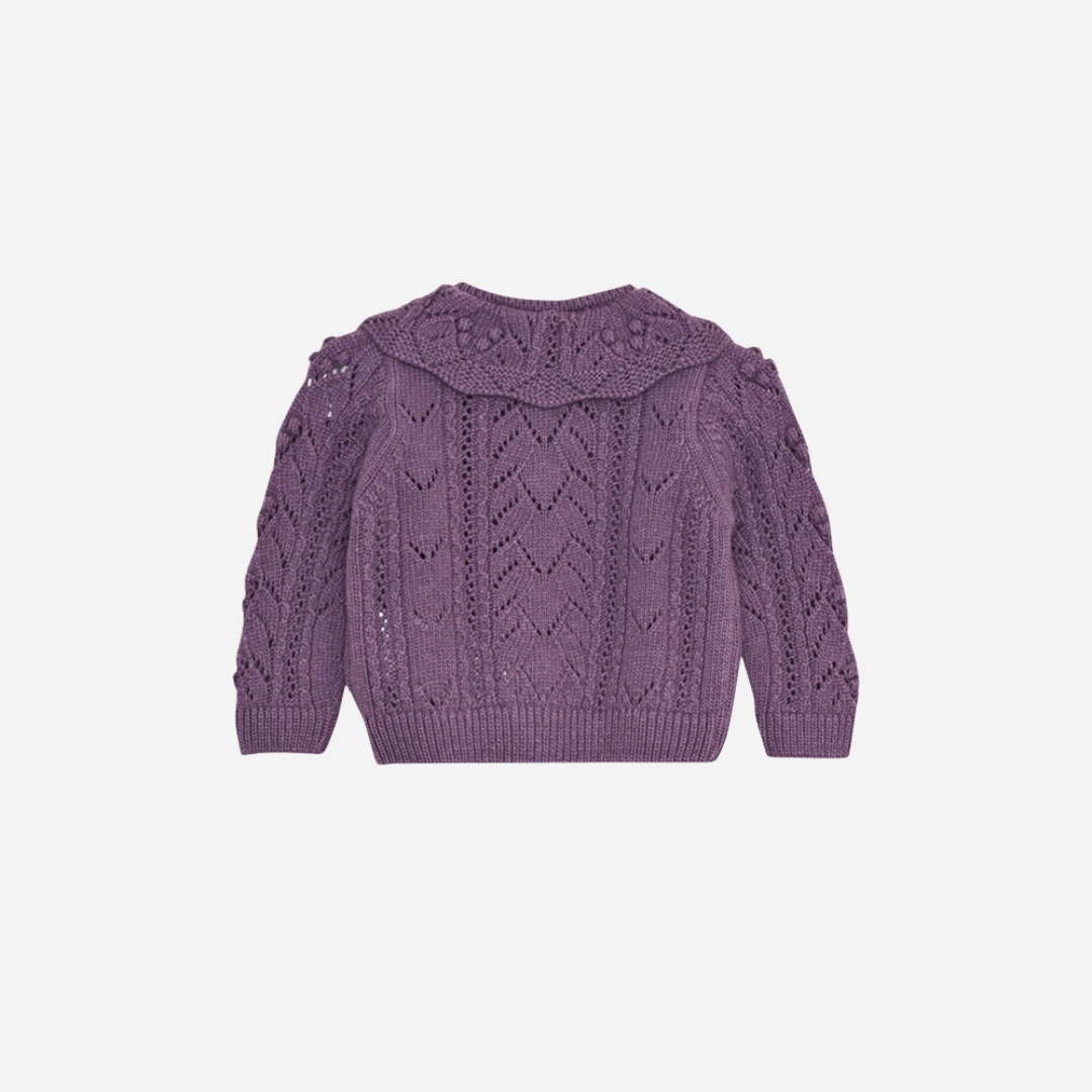 Sold at Bombon shop, this baby girl cardigan by The New Society features a delicate pointelle knit in soft lilac, a scalloped Peter Pan collar, and front button closure—perfect for adding a charming touch to any outfit. back