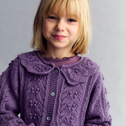 Sold at Bombon shop, this girls’ cardigan by The New Society features a rich lilac hue with an intricate pointelle knit pattern, scalloped Peter Pan collar, and front button closure—offering a refined and feminine layer for cooler days. model