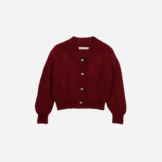 Sold at Bombon shop, this girls’ cardigan by The New Society comes in a rich burgundy knit with ribbed texture, heart-shaped buttons, and a cozy, slightly cropped fit—perfect for layering with a sweet, stylish touch. front