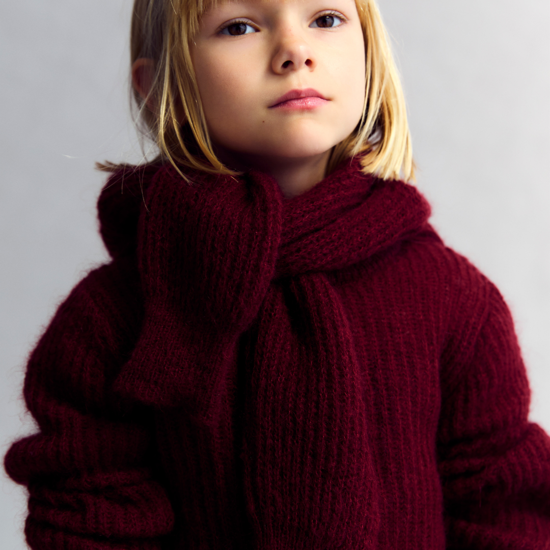 Sold at Bombon shop, this girls’ cardigan by The New Society comes in a rich burgundy knit with ribbed texture, heart-shaped buttons, and a cozy, slightly cropped fit—perfect for layering with a sweet, stylish touch. model
