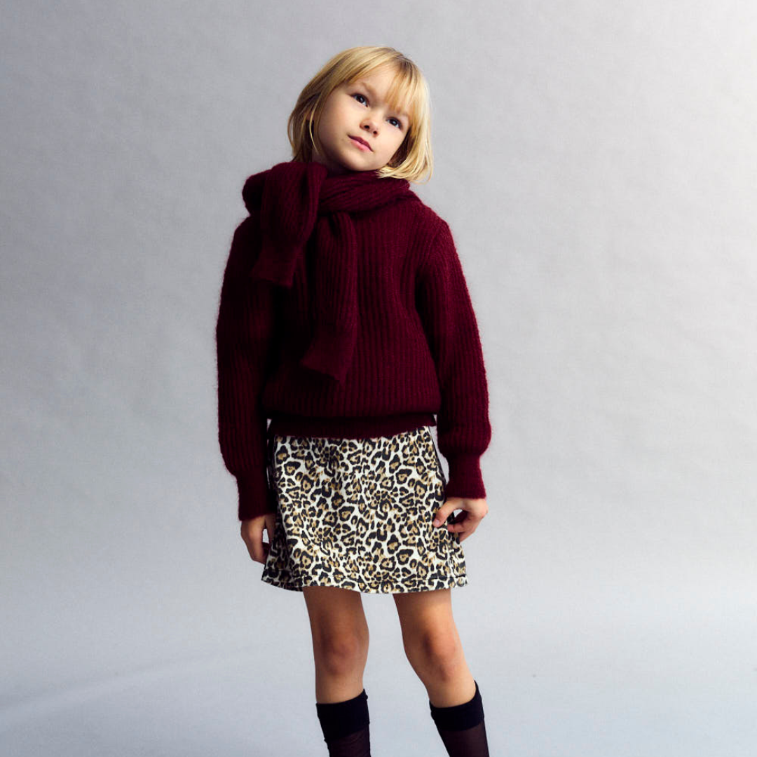 Sold at Bombon shop, this girls’ cardigan by The New Society comes in a rich burgundy knit with ribbed texture, heart-shaped buttons, and a cozy, slightly cropped fit—perfect for layering with a sweet, stylish touch. model