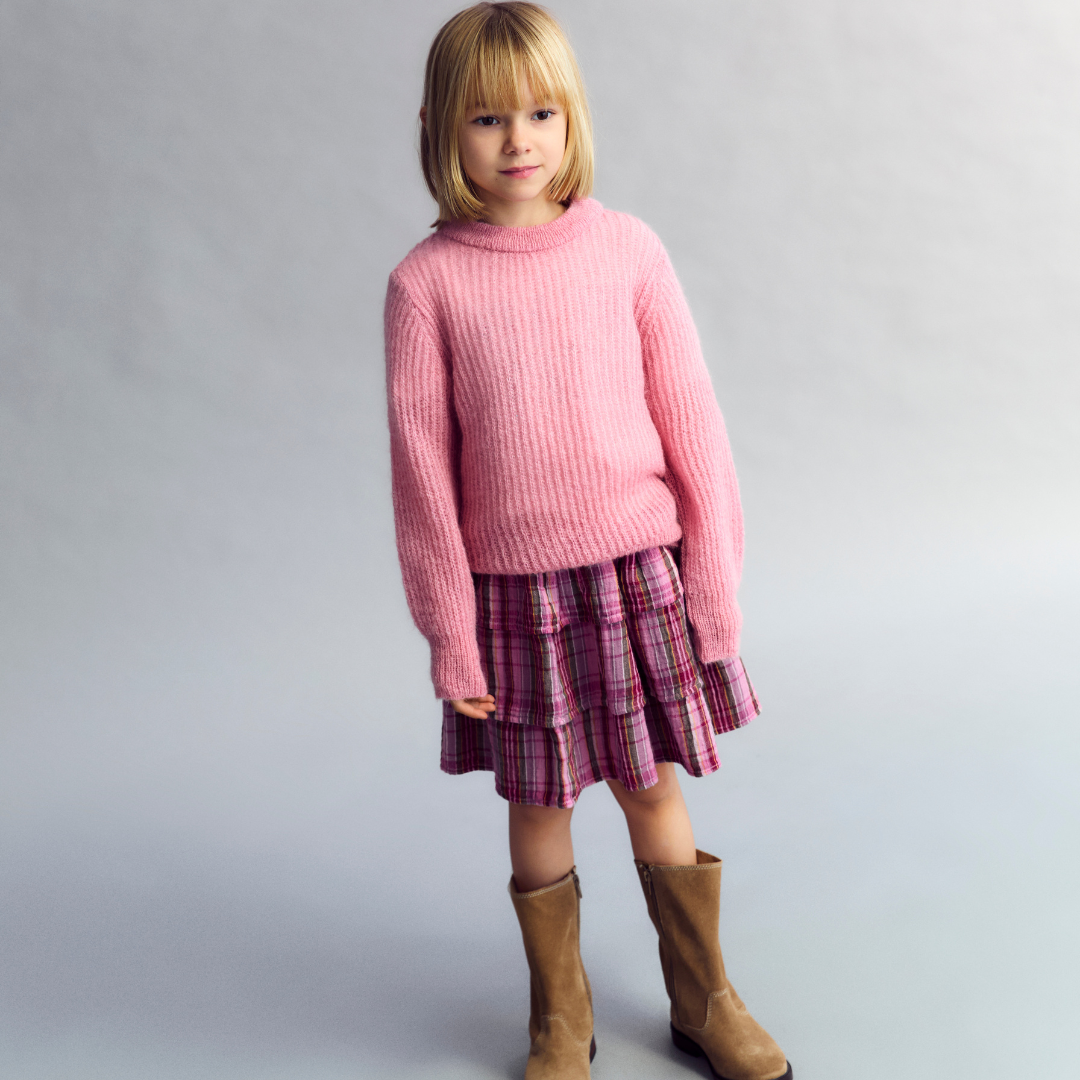 Sold at Bombon shop, this girls’ jumper by The New Society comes in a soft pink ribbed knit with a classic crew neckline and relaxed fit—perfect for cozy, everyday layering with a sweet touch. model