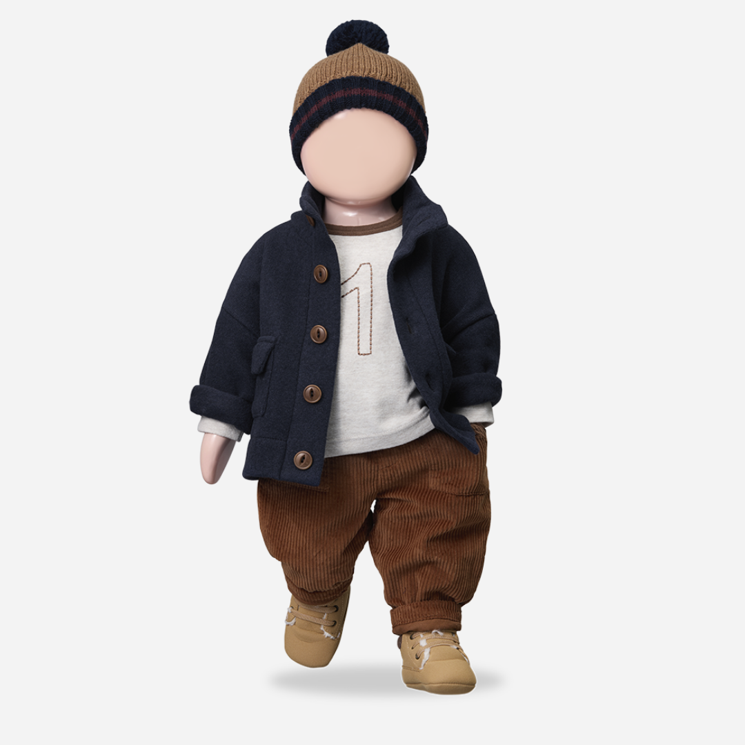 Doll wearing a navy coat, brown pants, and a knit hat on a light gray background