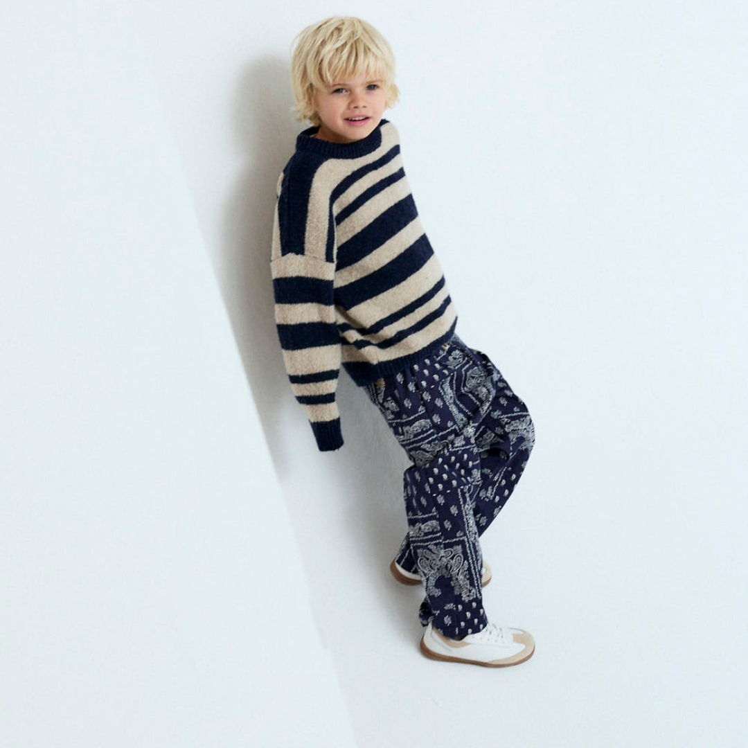 Sold at Bombon shop, these baby and toddler boy pants by The New Society feature a matching navy and white bandana print with an elastic waistband for an easy, comfortable fit—perfect for pairing with the coordinated shirt or mixing with basics. model view