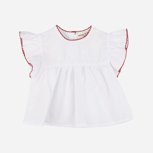Sold at Bombon Shop, designed by Babe & Tess, white cotton blouse with flutter sleeves, red scalloped trim details, relaxed fit, and classic summer styling, paired perfectly with the matching striped bloomers.